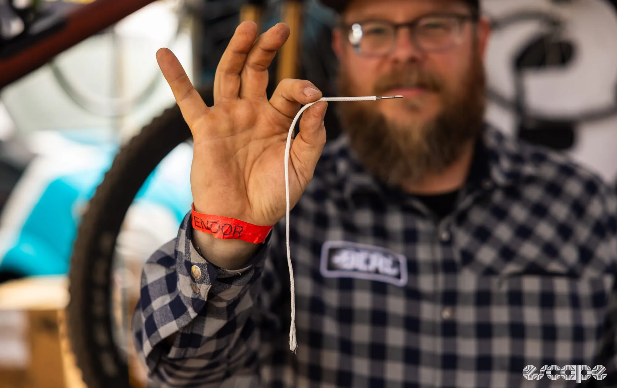A white BERD polymer spoke held up to show its flexible construction and threaded end